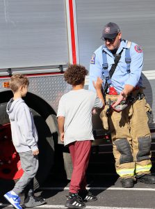 Students high five a Watervliet firefighter as they stand in front of a fire truck