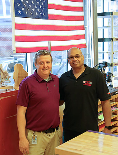 Technology teacher stands next to the representative from the Gene Haas Foundation following check presentation 