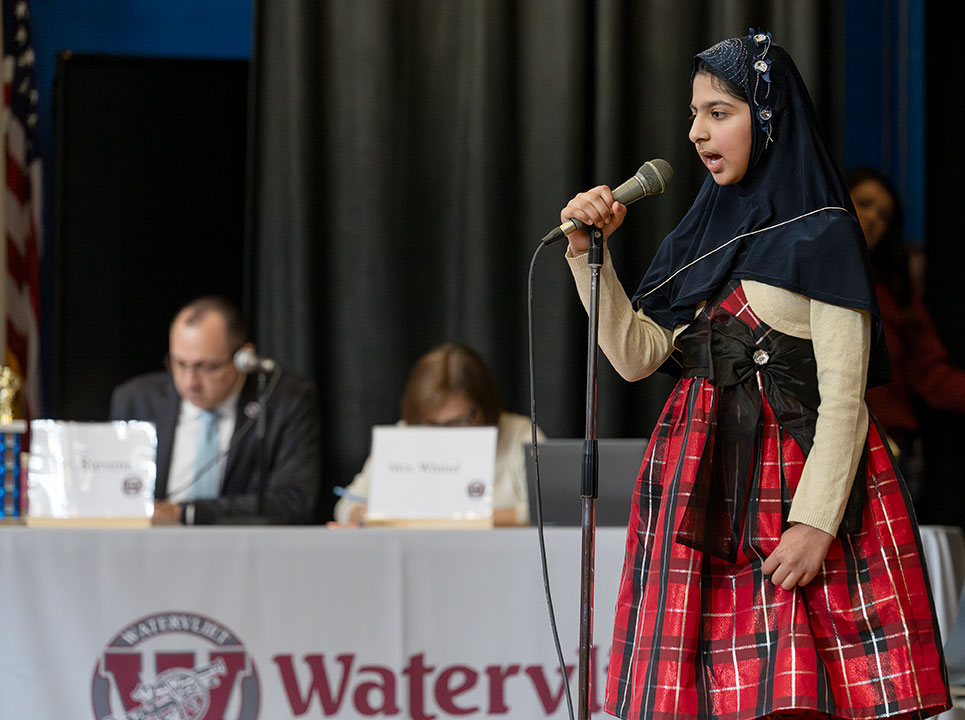 Spelling bee champion speaks into microphone during the competition
