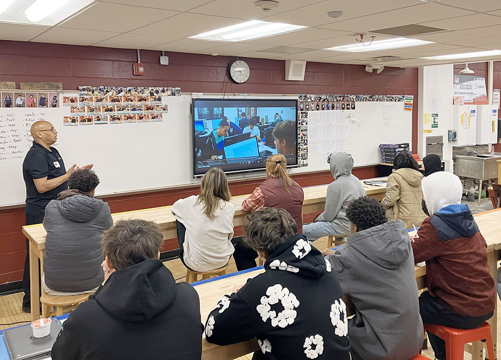 Education specialist stands at front of classroom and speaks to a group pf students 