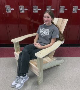 A student sits on an Adirondack chair built during STEM camp