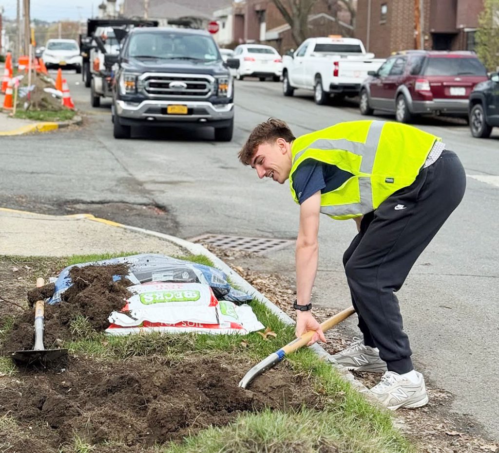 A student shovels dirt preparing the ground to plant a tree 