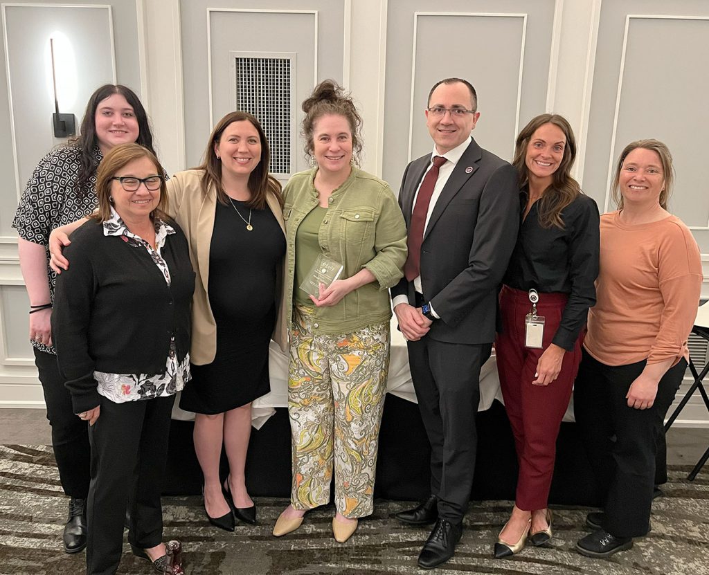 Watervliet administrator holds an award while standing next to the superintendent, other school leaders and Board of Education members