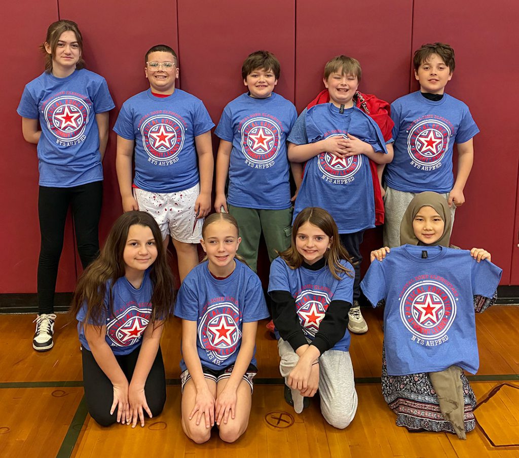 Students who received the Capital Zone Physical Education Leadership award, stand together in the gym wearing special tee shirts