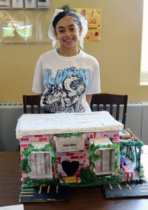 A student stands near their collaborative city project display