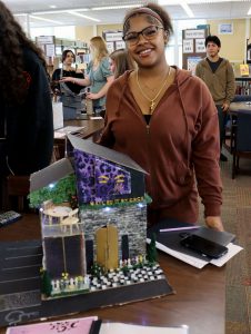 A student stands near a City Collaborative project that is on display