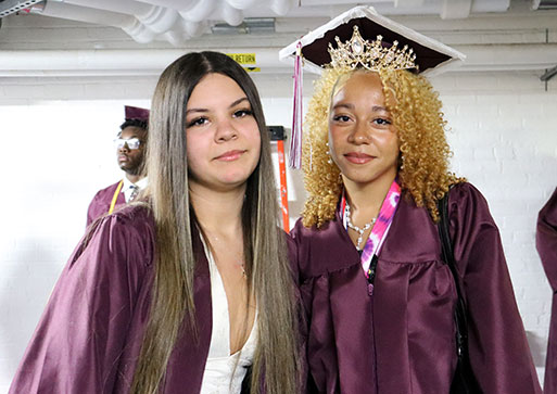Two graduates dressed in caps and gowns smiling
