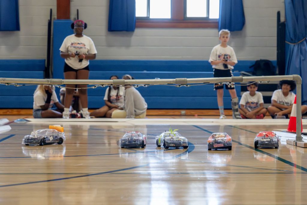 Students stand at the starting line holding remote controllers and waiting for the race to begin