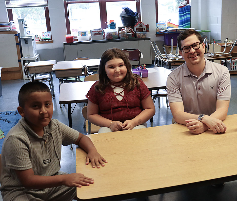 New assistant principal sits at a table with two elementary school students