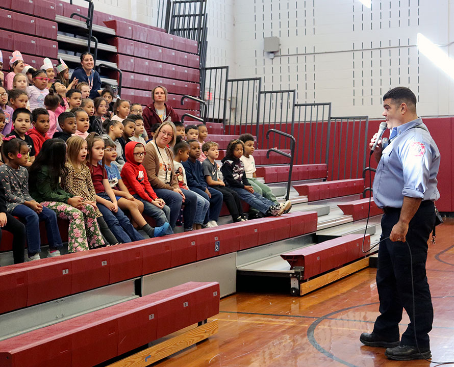 A firefighter shares safety tips with a group of students and teachers