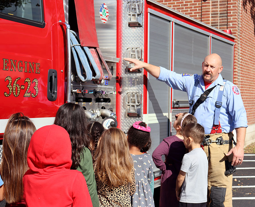 A firefighter explains the various equipment found on a fire truck to group of students